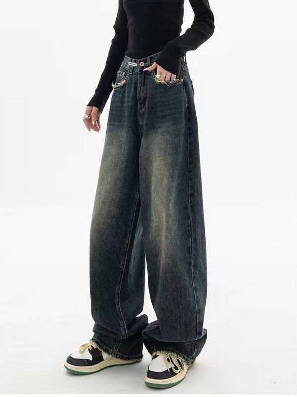 Vrouw in zwarte top en wijde, vintage jeans met sneakers. Modetrend, casual streetwear, comfortabele denimstijl, urban outfit.
