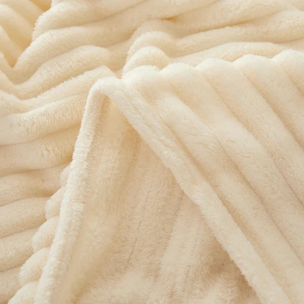 Zachte, crèmekleurige fleece deken met geribbelde textuur, ideaal voor warme, comfortabele nachten. Perfecte aanvulling op slaapkamerinterieur.