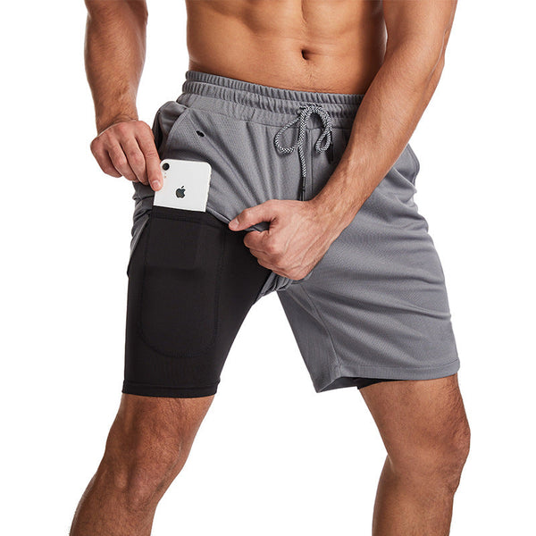 Man in grijze sportshorts met zijvak, toont smartphone-opslag. Ideaal voor hardlopen, fitness. Comfortabele, ademende stof.