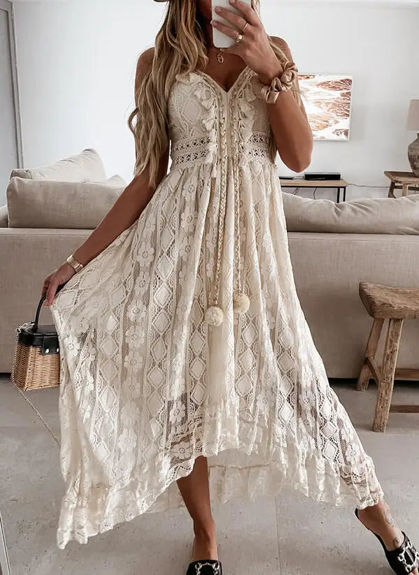 Vrouw in elegante, witte kanten zomerjurk met pompons, staand in moderne woonkamer. Perfecte boho-chic outfit voor zomerse dagen.