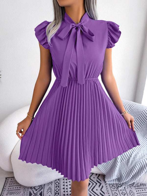 Vrouw in paarse geplooide jurk met strik, korte mouwen, elegante mode, trendy dameskleding, stijlvolle outfit voor speciale gelegenheden.