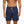 Donkerblauwe zwembroek met palmbomenprint en oranje trekkoord, gedragen door man. Perfect voor strandmode en zomerse zwemkleding.
