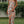 Vrouw in strapless bloemenjurk met split, staand op gras voor witte houten schutting. Zomermode, elegante dameskleding, casual chique stijl.