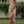 Vrouw in bloemenjurk met hoge split, lachend in tuin. Zomermode, elegante dameskleding, casual chique stijl, witte sandalen.