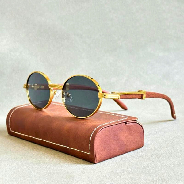 Ronde zonnebril met gouden montuur en donkere glazen op een bruine etui. Stijlvolle unisex zonnebril, modieus accessoire voor elke gelegenheid.