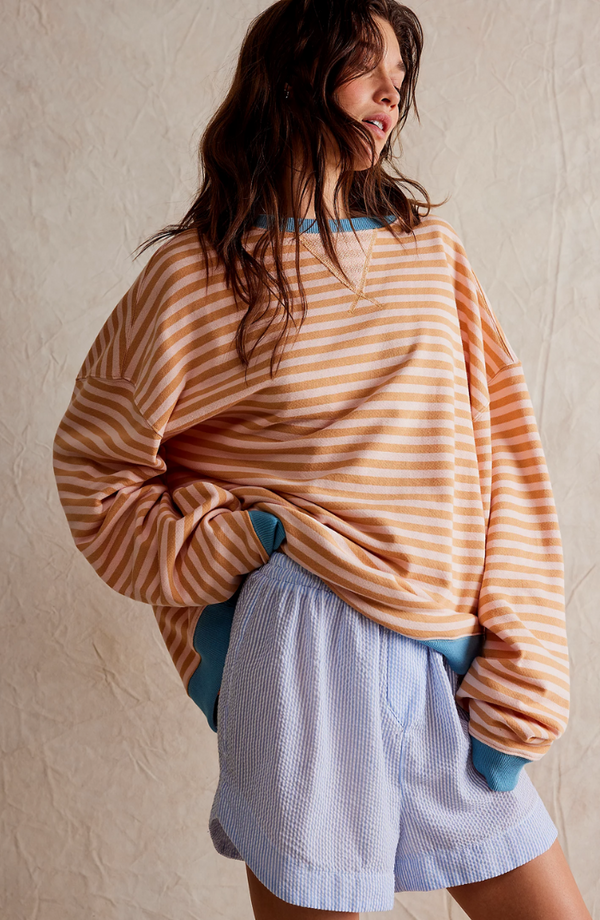 Vrouw in oversized gestreepte trui en blauwe shorts, casual mode, comfortabele kleding, trendy dameskleding, modieuze outfit, ontspannen stijl.