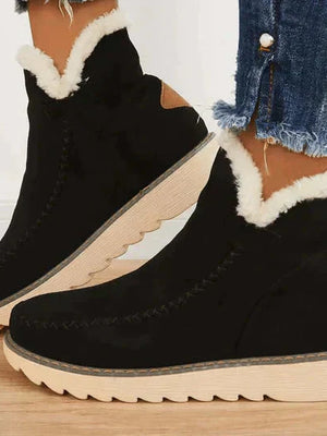 Zwarte suède laarzen met witte bontvoering en dikke rubberen zool, gedragen met gerafelde jeans. Perfect voor wintermode en casual stijl.
