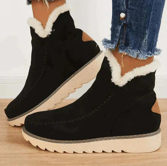 Zwarte suède laarzen met witte bontvoering en dikke rubberen zool, gedragen met gerafelde jeans. Perfect voor wintermode en casual stijl.