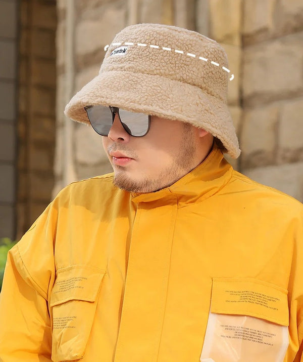Man met beige teddy bucket hat en zonnebril, draagt een gele jas. Stijlvolle wintermode, trendy accessoires, buitenkleding.