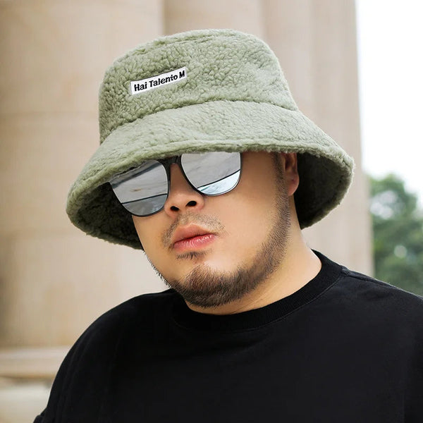Man met groene teddy bucket hat en spiegelzonnebril, casual zwarte trui, buitenomgeving. Modieuze herenkleding, trendy accessoires.