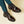 Donkerbruine leren loafers met dikke zolen en decoratieve stiksels, gedragen met gestreepte sokken en groene broek. Stijlvolle herenschoenen.