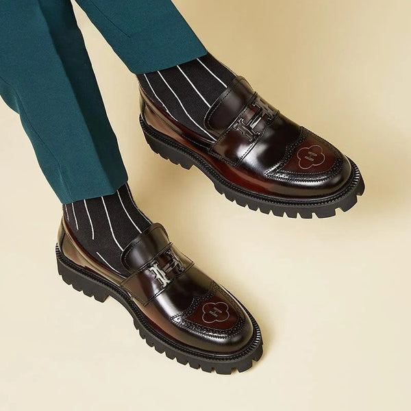 Donkerbruine leren loafers met dikke zolen en decoratieve stiksels, gedragen met gestreepte sokken en groene broek. Stijlvolle herenschoenen.