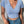 Vrouw in blauwe crop top met V-hals en jeans, draagt een transparante schoudertas. Modieuze zomerkleding, casual damesoutfit.