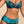 Vrouw in tropische bikini met bladerenprint op strand. Hoog getailleerde bikini, kleurrijk ontwerp, strandmode, zomerse zwemkleding.