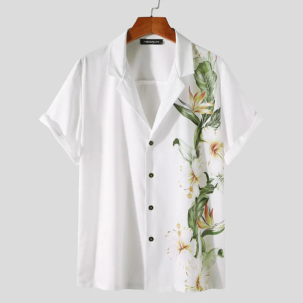 Witte herenoverhemd met korte mouwen en tropische bloemenprint, hangend aan een houten hanger. Perfect voor zomerse casual outfits.