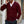 Man in bordeauxrode cardigan met knopen, witte overhemdkraag zichtbaar, pratend op smartphone. Stijlvolle herenkleding, casual mode.