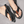 Zwarte teenslippers met gevlochten band en bruine leren details, gedragen op een betonnen ondergrond. Comfortabele zomerschoenen voor heren.