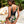 Vrouw in tropisch badpak met bloemenprint, staand bij strandstoel en planten. Zomermode, strandkleding, vakantie, tropisch design.