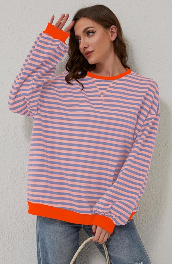 Vrouw in gestreepte trui met roze en blauwe strepen, oranje boorden, casual look, modieuze dameskleding, trendy outfit, witte achtergrond.