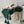Groene en beige gebreide dekens met kwastjes in een witte draadmand, decoratief interieuraccessoire, moderne woondecoratie, gezellige textielstijl.