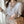 Vrouw in elegante witte blouse met V-hals en beige details, draagt beige broek en handtas. Modieuze dameskleding, stijlvolle outfit voor kantoor.