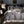 Luxe grijs dekbedovertrek op kingsize bed met gouden accenten, moderne slaapkamerinrichting, nachtkastje met lamp, comfortabele stoel.
