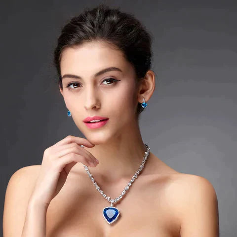 Vrouw met elegante blauwe saffier ketting en oorbellen, zilveren sieraden, luxe modeaccessoires, stijlvolle uitstraling, grijze achtergrond.