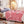 Roze fleece deken op bed in moderne slaapkamer, met sierkussens en vloerlamp. Gezellige en stijlvolle inrichting voor comfortabele nachtrust.