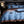 Luxe blauw en bruin dekbedovertrek op kingsize bed met kussens, boek en bril. Hoogwaardige slaapkamerinrichting, modern design.