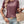 Vrouw in casual outfit met bordeauxrood T-shirt, denim shorts en gevlochten rieten tas. Trendy zomermode, accessoires, boho-stijl.