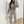Vrouw in grijs trainingspak met crop top en hoodie, poseert voor spiegel met smartphone. Casual mode, comfortabele loungewear, trendy outfit.