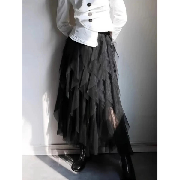 Witte blouse met zwarte knopen, gecombineerd met een lange, zwarte, gelaagde tule rok en zwarte laarzen. Elegante damesmode, stijlvolle outfit.