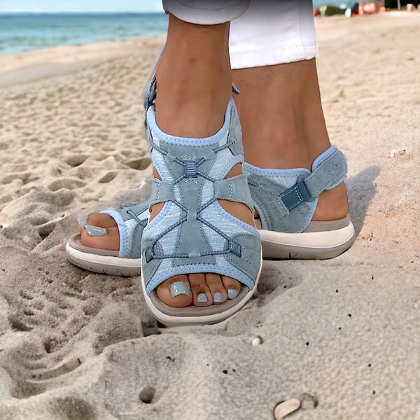 Lichtblauwe sandalen voor dames op zandstrand, comfortabele zomerschoenen, open teen, verstelbare bandjes, ideaal voor strandwandelingen.