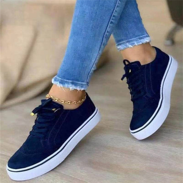 Zwarte lage damessneakers met ronde neus en witte zool, gecombineerd met blauwe jeans. Casual gevulkaniseerde schoenen, ideaal voor wandelen.