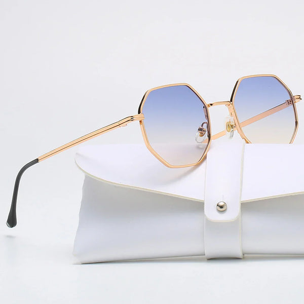 Vintage polygonale zonnebril met metalen frame, blauw getinte glazen en witte etui. Trendy damesaccessoire voor retro reizen en autorijden.