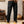 Man in casual outfit met zwarte cargobroek en bruine werklaarzen, staand in een moderne woonkamer. Stijlvolle herenkleding, comfortabele vrijetijdskleding.