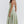 Vrouw in elegante, lichtgroene midi-jurk met spaghettibandjes, perfecte zomeroutfit. Stijlvolle mode, trendy dameskleding, casual chic.