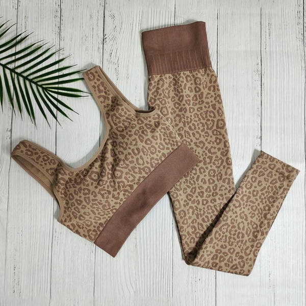 Luipaardprint sportset voor dames, bestaande uit een sportbeha en legging, op witte houten achtergrond. Perfect voor yoga en fitness.