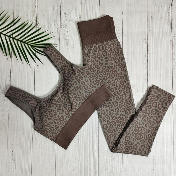 Luipaardprint sportbeha en legging set op witte houten achtergrond met palmblad, stijlvolle dames sportkleding, fitnessmode, trendy activewear.