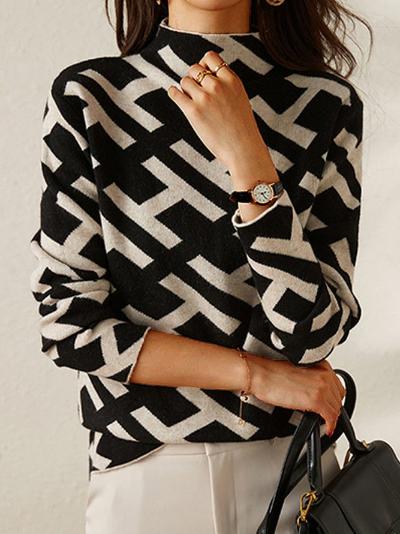 Damestrui met zwart-wit geometrisch patroon, lange mouwen en col, gecombineerd met een zwarte handtas. Perfect voor herfstmode en casual outfits.