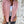 Vrouw draagt roze corduroy jack met capuchon, witte top en zwarte jeans tegen een verweerde muur. Modieuze dameskleding, casual stijl.