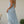 Vrouw in lichtblauwe zomerjurk met halternek, staand in tuin. Elegante maxi-jurk, perfect voor zomerse dagen. Casual en stijlvol design.