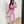 Vrouw in roze trainingspak met crop top, houdt een beige handtas vast en maakt een selfie in een moderne kamer. Sportieve mode, casual outfit.