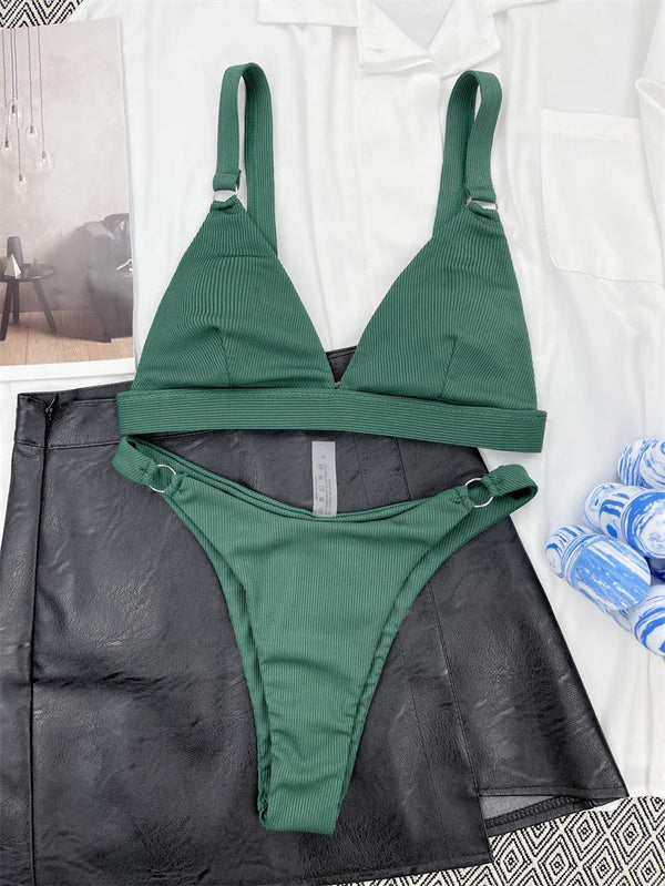 Groene ribgebreide bikini met triangel top en hoge taille slip, gestyled op zwarte leren rok en witte blouse. Perfecte strandkleding voor dames.
