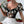 Vrouw in zwarte bloemen crop top met transparante mouwen, witte rok, houdt rode roos vast. Trendy damesmode, romantische outfit, elegante stijl.