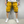 Man in gele cargoshorts en witte sneakers tegen grijze achtergrond. Modieuze zomerkleding, casual stijl, comfortabele herenshorts.