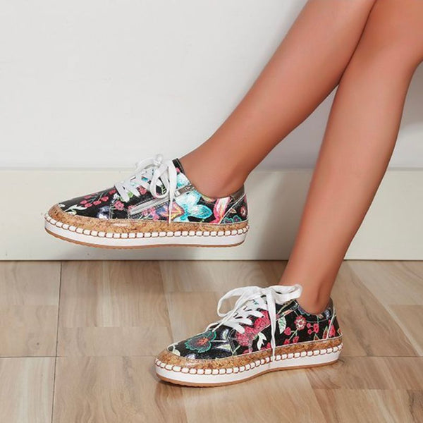 Vrouwelijke benen dragen kleurrijke, gebloemde sneakers met witte veters op houten vloer. Modieuze damesschoenen, casual stijl, trendy ontwerp.