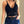 Vrouw in zwarte kanten crop top met spaghettibandjes en diepe V-hals, gecombineerd met donkerblauwe jeans en riem. Trendy damesmode.