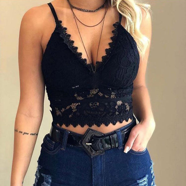 Vrouw in zwarte kanten crop top met spaghettibandjes en diepe V-hals, gecombineerd met donkerblauwe jeans en riem. Trendy damesmode.