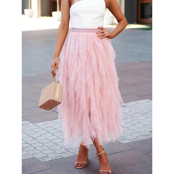 Vrouw in elegante roze tule rok en witte top, draagt een beige handtas en sandalen. Perfecte zomermode, stijlvolle outfit voor speciale gelegenheden.